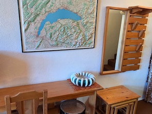 A room with a wooden desk, a chair, a small round stool, a decorative object on the desk, a map on the wall, and a mirror with a wooden frame. - Avoriazien style apartment with view - 6 guests (Avoriaz)