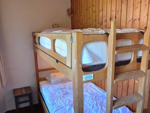 Een stapelbed met een ladder, een klein tafeltje en een bordje in het Frans.