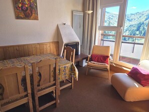 A cozy room with a wooden table, chairs, a sofa, a fireplace, and a large window with a mountain view. - Avoriazien style apartment with view - 6 guests (Avoriaz)