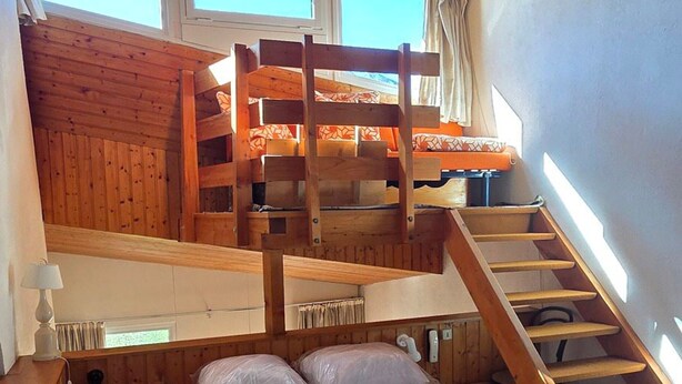 A wooden bunk bed with a staircase leading to an upper bunk, a bedside table, and a window with curtains. - Avoriazien style apartment with view - 6 guests (Avoriaz)