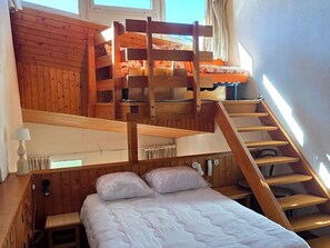 A wooden bunk bed with a staircase leading to an upper bunk, a bedside table, and a window with curtains. - Avoriazien style apartment with view - 6 guests (Avoriaz)