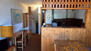 A wooden interior with a dining area, a kitchen, and a patterned rug. - Avoriazien style apartment with view - 6 guests (Avoriaz)