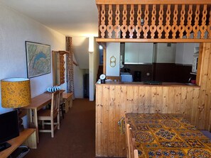 A wooden interior with a dining area, a kitchen, and a patterned rug. - Avoriazien style apartment with view - 6 guests (Avoriaz)