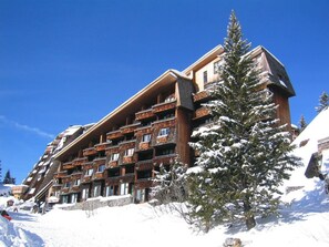 A multi-story hotel with balconies, surrounded by snow-covered trees and a clear blue sky. - Avoriazien style apartment with view - 6 guests (Avoriaz)