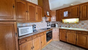 A kitchen with wooden cabinets, a microwave, a coffee maker, and a toaster. - Countryside house in Berry, near Loire Castles (Clion)
