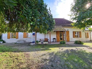 Ein Haus mit Ziegeldach, Holzfensterläden, einem Basketballkorb und einem kleinen Garten.