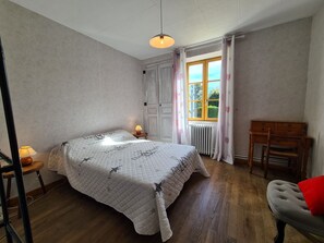 A bedroom with a bed, a desk, a chair, a radiator, and a window with curtains. - Countryside house in Berry, near Loire Castles (Clion)