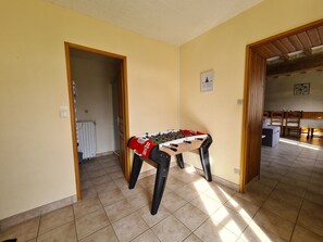 Um quarto com mesa de futebol, radiador e porta que dá para outro cômodo.