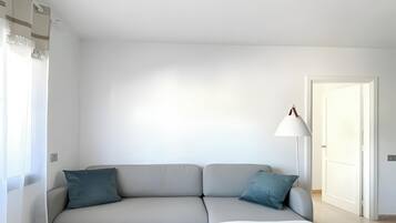 Una sala de estar moderna con un sofá gris, una mesa de centro de madera redonda y una lámpara de pie.