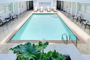 A rectangular indoor swimming pool with lounge chairs and tables on either side. - Walk to Beach! Old Naples Condo w/ Pool Access (Naples)