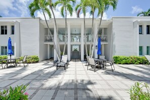 Ein Hotel mit überdachter Außenbereich, Palmen und einem zweistöckigen Gebäude.