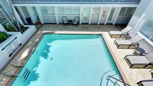 Piscina rectangular con tablon y sillas de descanso alrededor.
