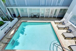 Ein rechteckiger Pool mit Sprungbrett und Liegestühlen darum.