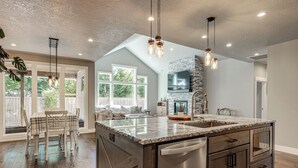 A spacious kitchen with a large island, stainless steel appliances, and a stone accent wall. - Walk to Autzen Stadium: Eugene Getaway w/ Yard (Eugene)