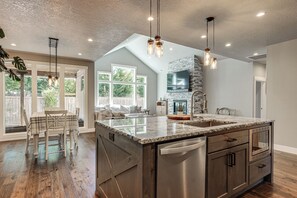 A spacious kitchen with a large island, stainless steel appliances, and a stone accent wall. - Walk to Autzen Stadium: Eugene Getaway w/ Yard (Eugene)