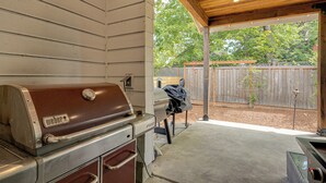 An outdoor barbecue area with a built-in grill, a covered patio, and a wooden fence in the background. - Walk to Autzen Stadium: Eugene Getaway w/ Yard (Eugene)
