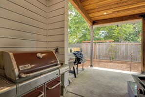An outdoor barbecue area with a built-in grill, a covered patio, and a wooden fence in the background. - Walk to Autzen Stadium: Eugene Getaway w/ Yard (Eugene)