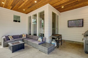 A covered patio with a wicker sofa, a coffee table, and a grill. - Walk to Autzen Stadium: Eugene Getaway w/ Yard (Eugene)