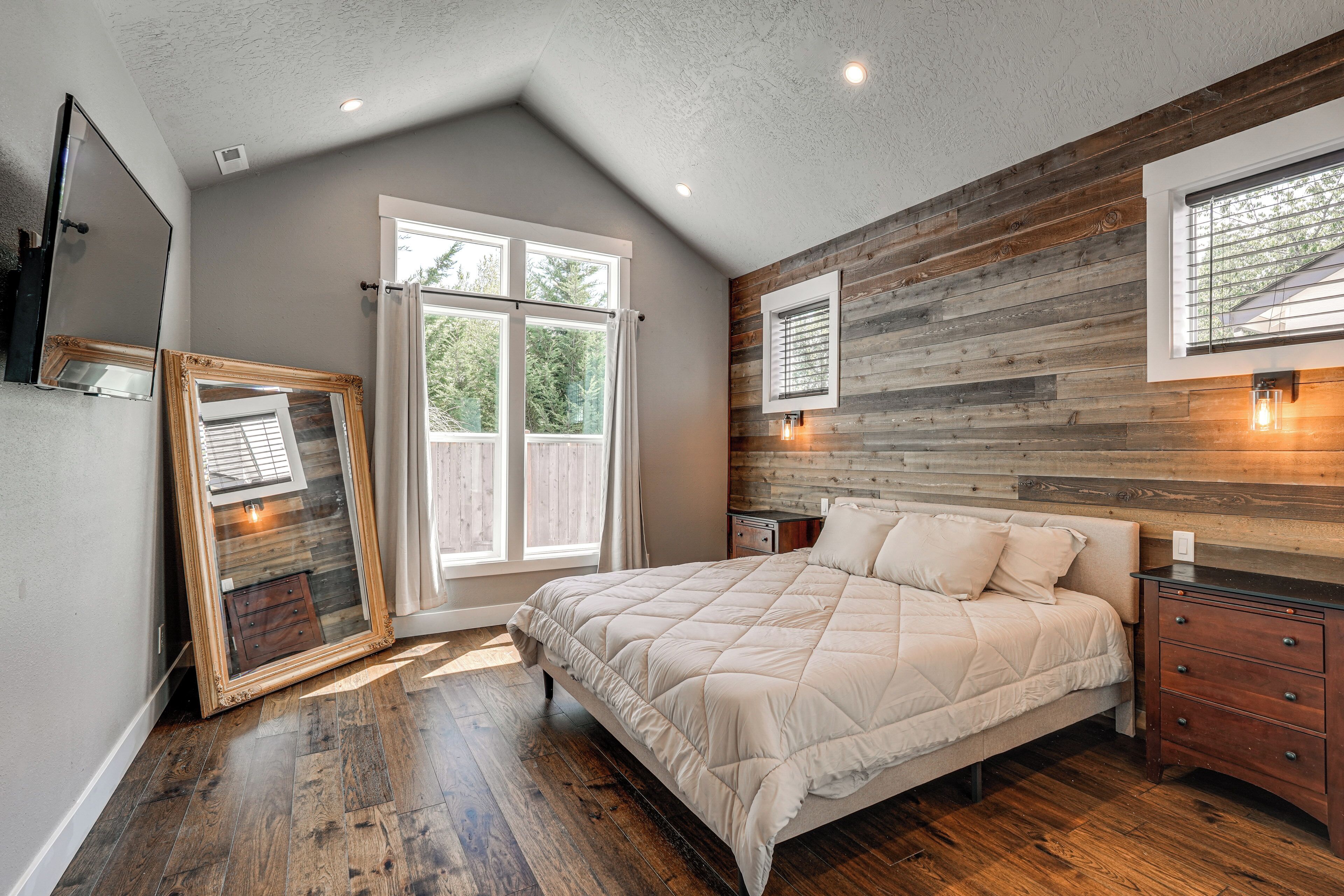 Ein Schlafzimmer mit einem großen Bett, Holzvertäfelung an den Wänden, einem Fenster mit Vorhängen und einem Nachttisch mit Lampe.