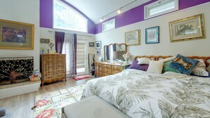 Quarto com cama, penteadeira e janela com cortinas.