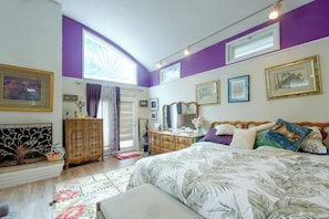 A bedroom with a bed, dresser, and a window with curtains.