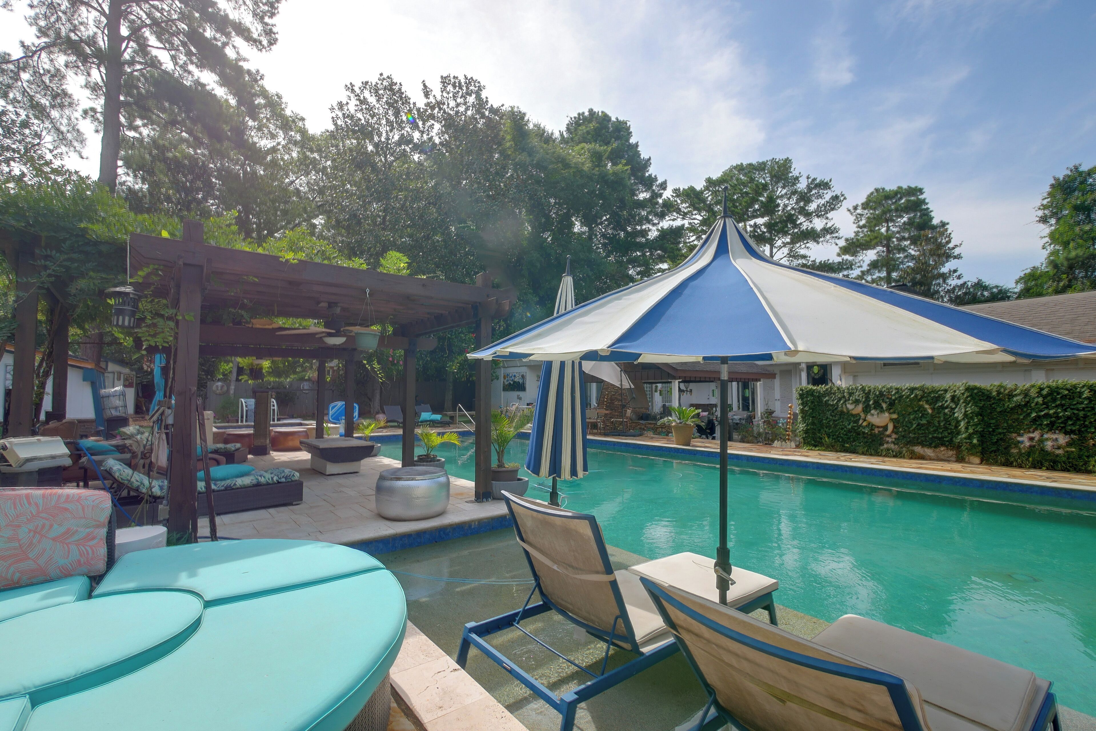 A pool area with lounge chairs and a pergola.