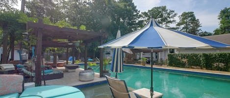 Un área de piscina con sillones de descanso y una pérgola.