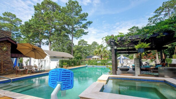 Piscina com uma escada flutuante azul, rodeada por espreguiçadeiras e guarda-sóis.