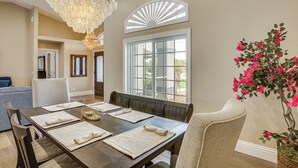 A dining area with a wooden table set for four, a chandelier, and a window with a view of the outdoors. - Boat Dock & Outdoor Kitchen! Port Charlotte Escape (Port Charlotte)