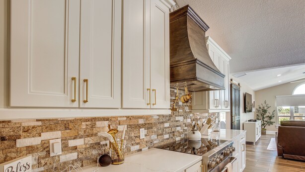 A kitchen with white cabinets, a stone backsplash, and a stainless steel range hood. - Boat Dock & Outdoor Kitchen! Port Charlotte Escape (Port Charlotte)