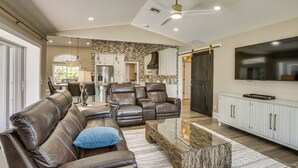 A spacious living room with a leather sofa, a glass coffee table, and a flat-screen TV mounted on the wall. - Boat Dock & Outdoor Kitchen! Port Charlotte Escape (Port Charlotte)