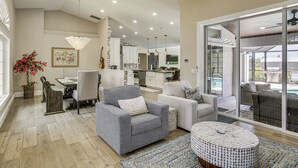 A spacious living area with a dining table, sofas, and a kitchen in the background. - Boat Dock & Outdoor Kitchen! Port Charlotte Escape (Port Charlotte)