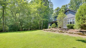 A well-maintained lawn with a house featuring a covered porch and a stone retaining wall. - Views, Hot Tub & Fire Pit! Luxe Blue Ridge Retreat (Blowing Rock)