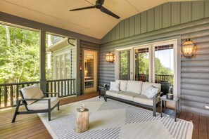 A covered porch with a sofa, chair, and table, featuring large windows and a ceiling fan. - Views, Hot Tub & Fire Pit! Luxe Blue Ridge Retreat (Blowing Rock)