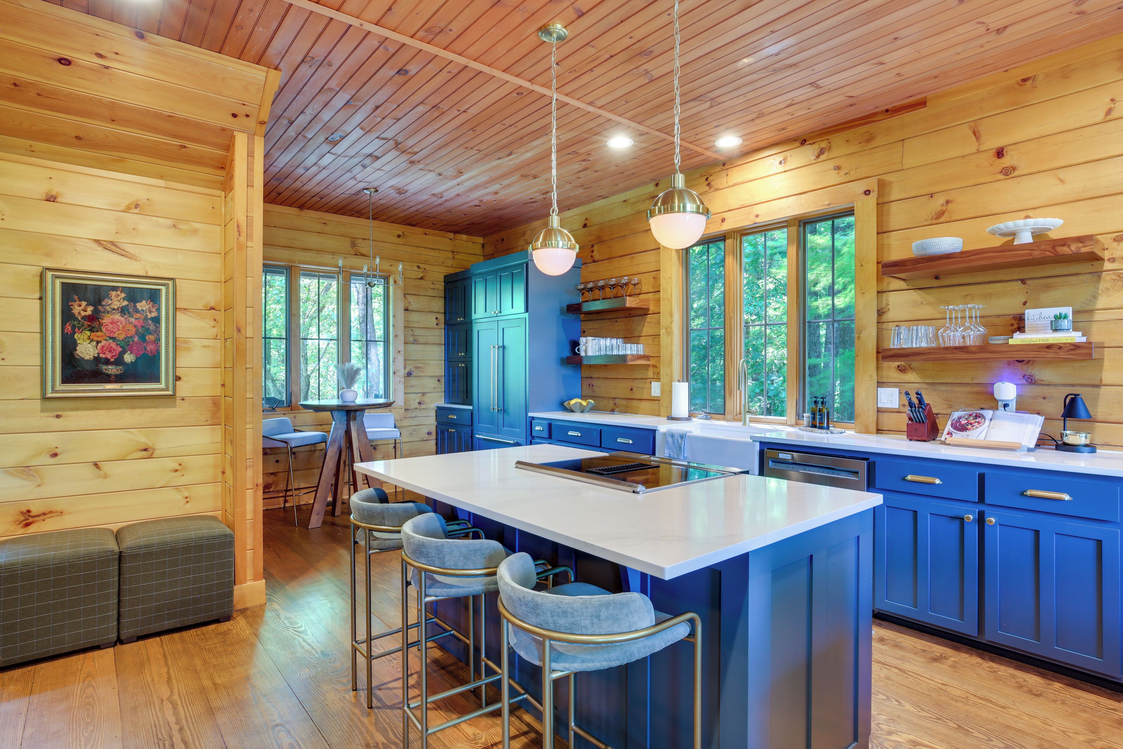 A modern kitchen with wooden walls, a large island, bar stools, and a dining area with a bench.