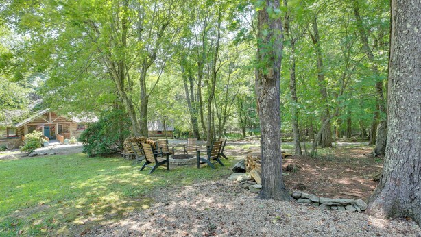 A wooden cabin with a porch, surrounded by a forested area with a fire pit and seating. - Views, Hot Tub & Fire Pit! Luxe Blue Ridge Retreat (Blowing Rock)