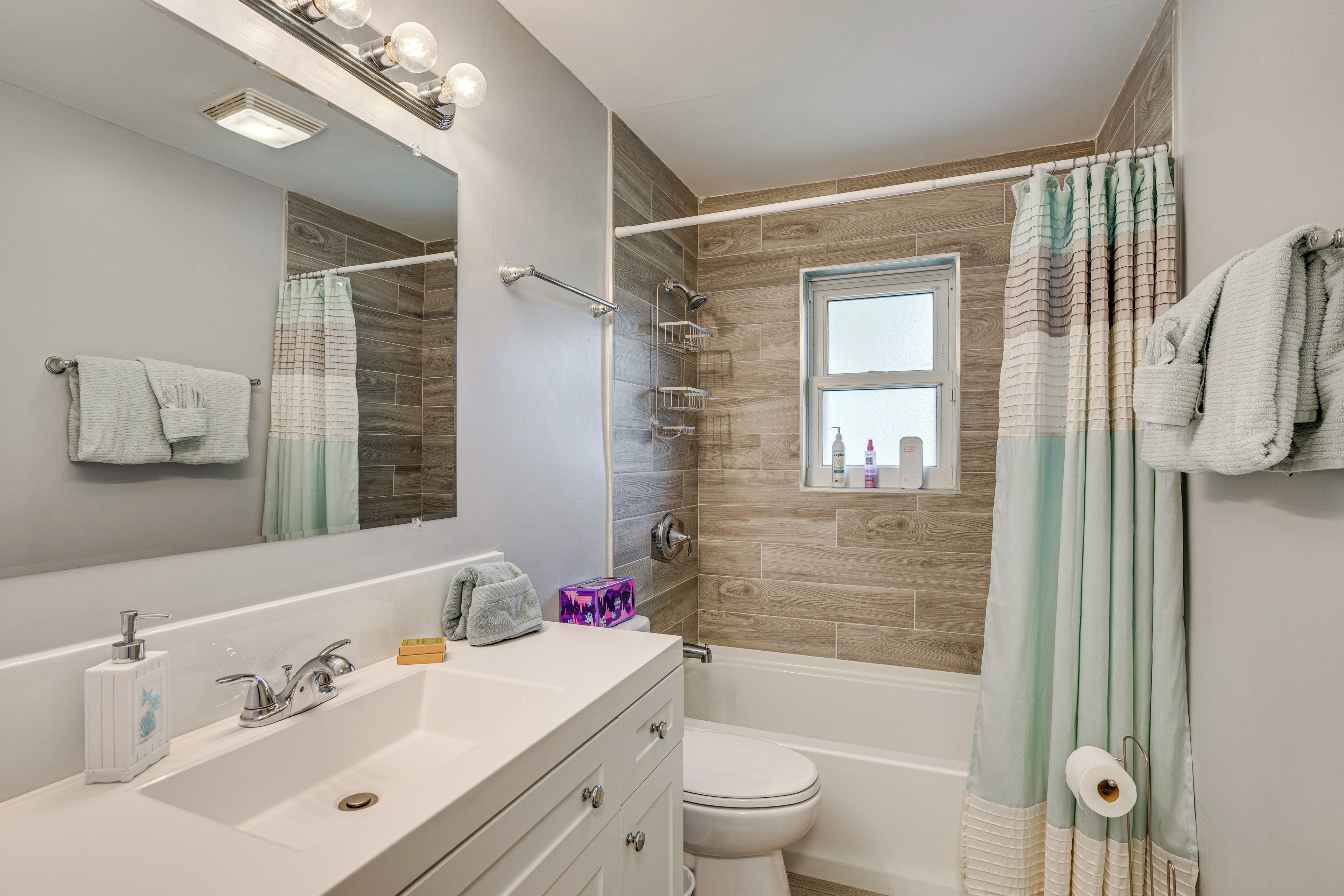 A modern bathroom with a vanity, a toilet, a shower, and a window.