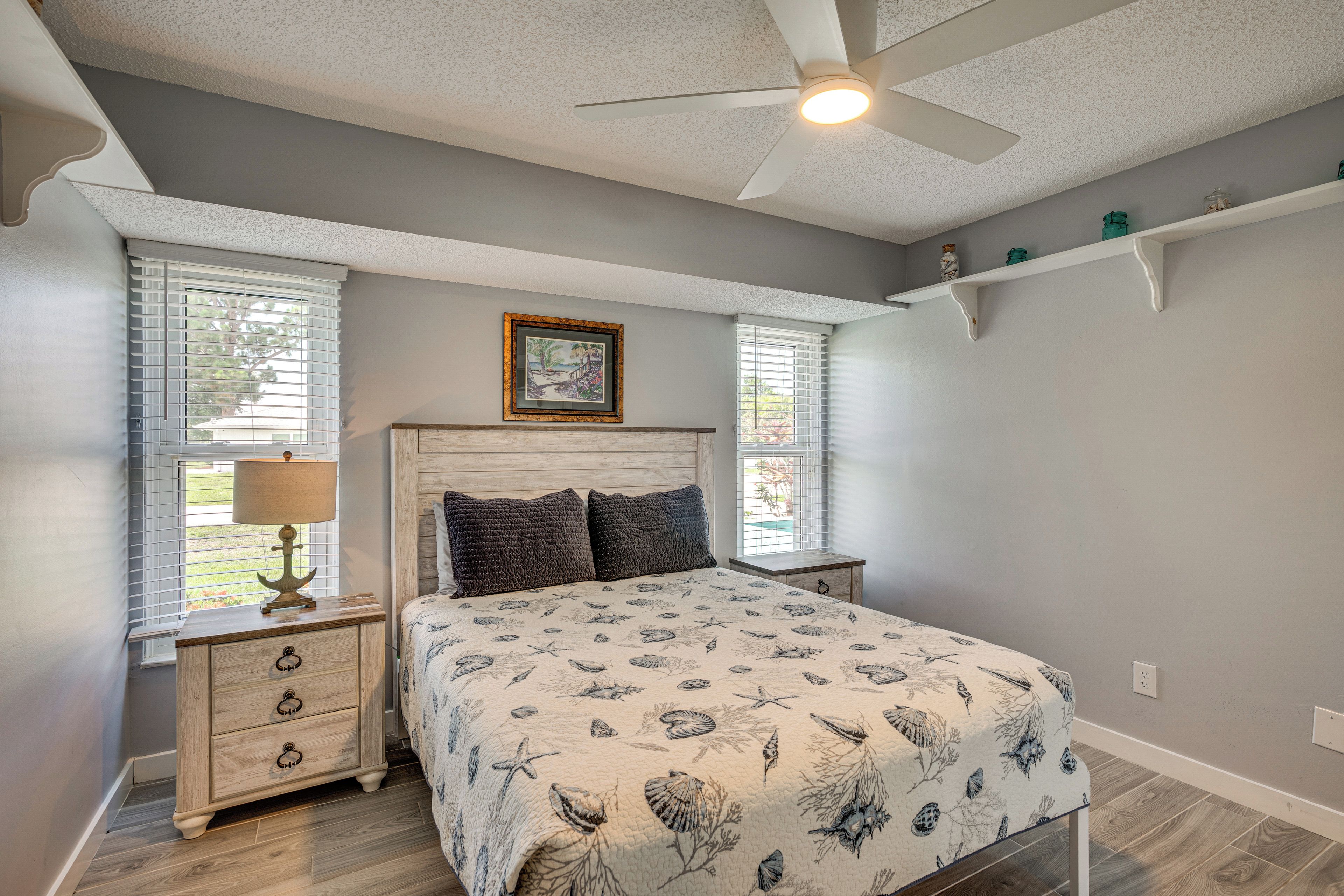 A bedroom with a bed, nightstands, a ceiling fan, and a window with blinds.