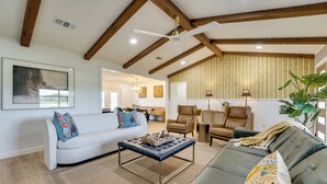 A spacious living room with a high ceiling, wooden beams, a white sofa, a leather couch, and a dining area. - Furnished Patio & Spacious Yard! Seguin Escape (Seguin)