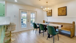 A dining area with a wooden table, green chairs, and a chandelier. - Furnished Patio & Spacious Yard! Seguin Escape (Seguin)