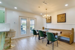 A dining area with a wooden table, green chairs, and a chandelier.
