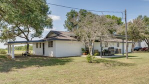 A single-story house with a covered porch, a small attached garage, and a lawn. - Furnished Patio & Spacious Yard! Seguin Escape (Seguin)
