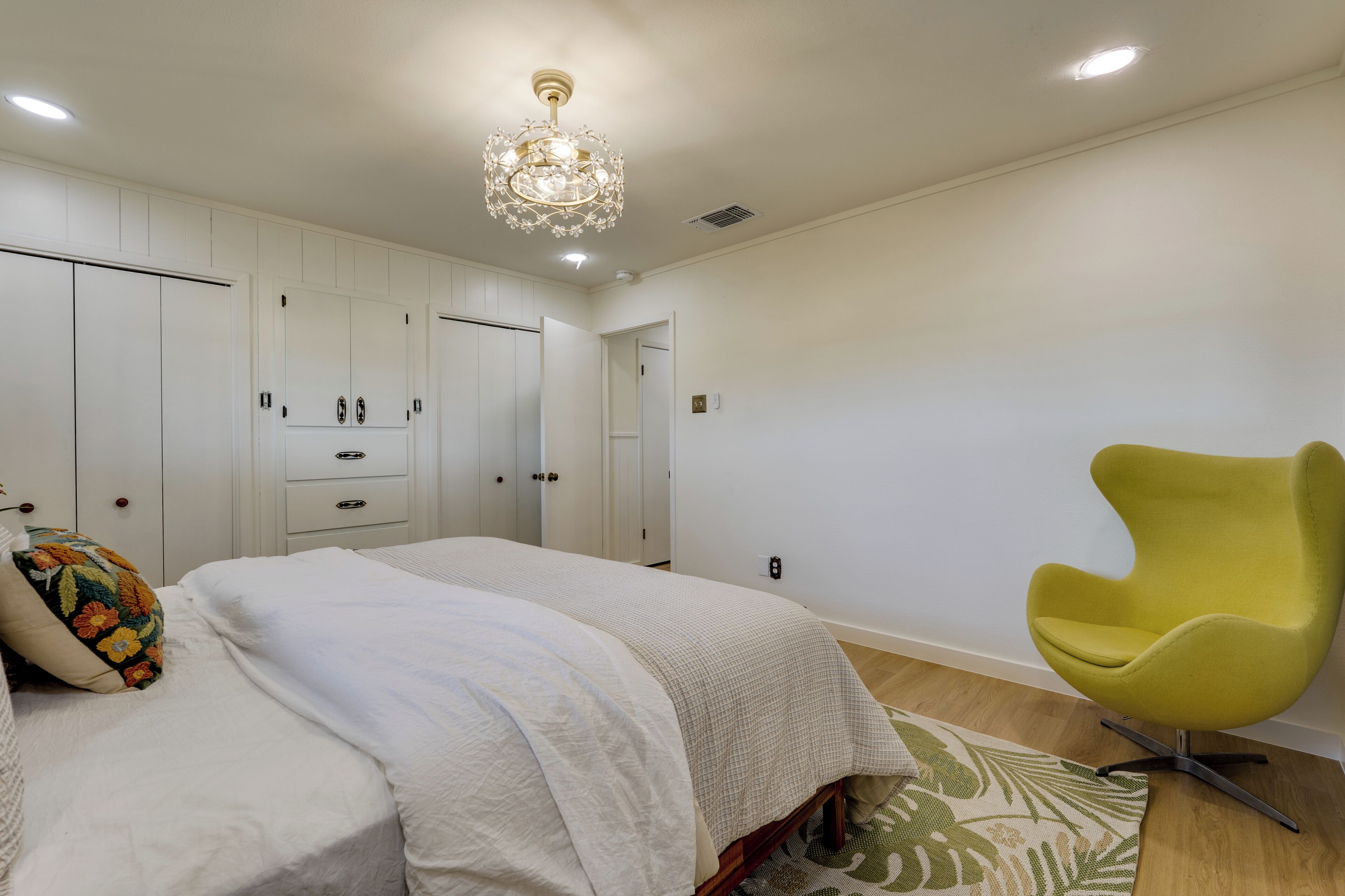 Un dormitorio con cama, una silla amarilla y un candelabro.