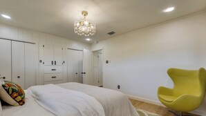 A bedroom with a bed, a yellow chair, and a chandelier. - Furnished Patio & Spacious Yard! Seguin Escape (Seguin)
