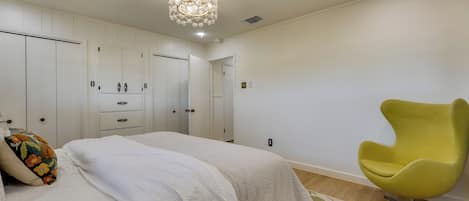 Un dormitorio con cama, una silla amarilla y un candelabro.