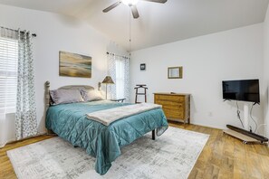 Ein Schlafzimmer mit einem Bett, einem Schminktisch, einem Fernseher und einem Deckenventilator.