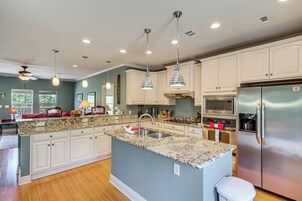 A modern kitchen with white cabinetry, a granite countertop, stainless steel appliances, and pendant lighting.