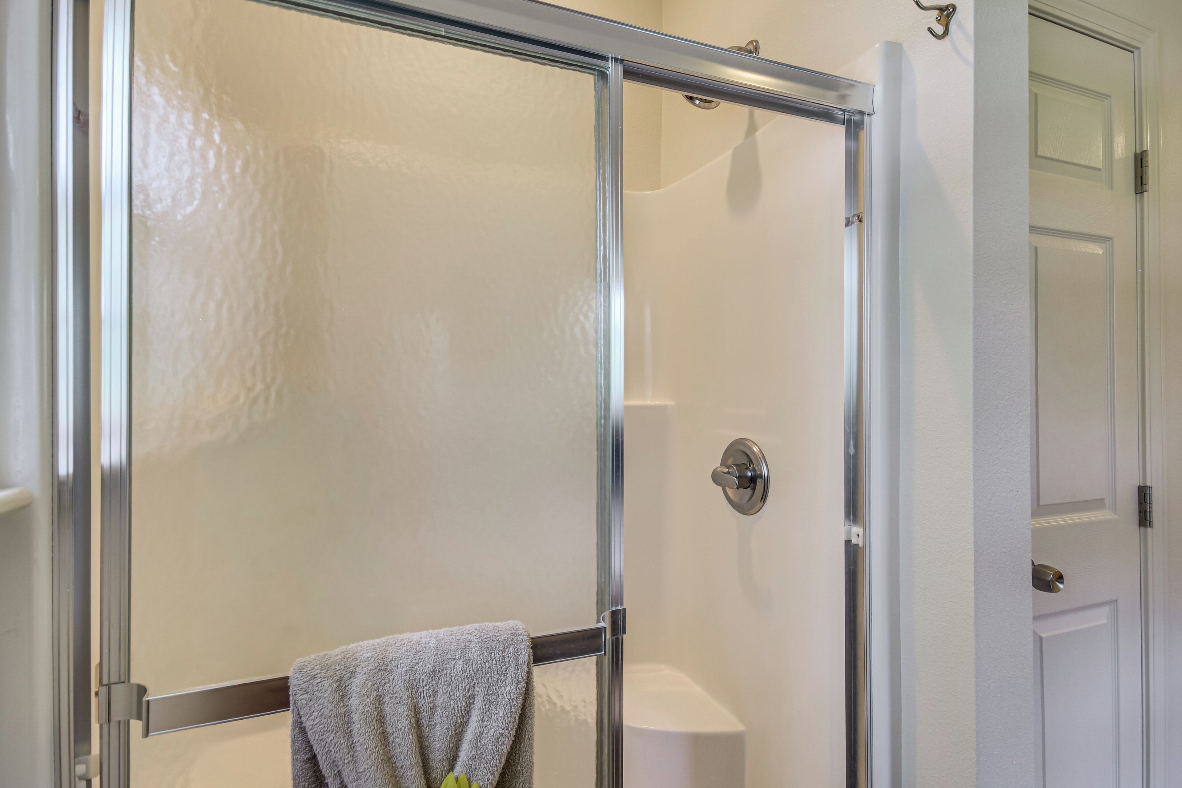 A glass-enclosed shower with a towel rack and a toilet visible.