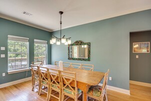A dining area with a wooden table and chairs, a chandelier, and a large mirror on the wall.