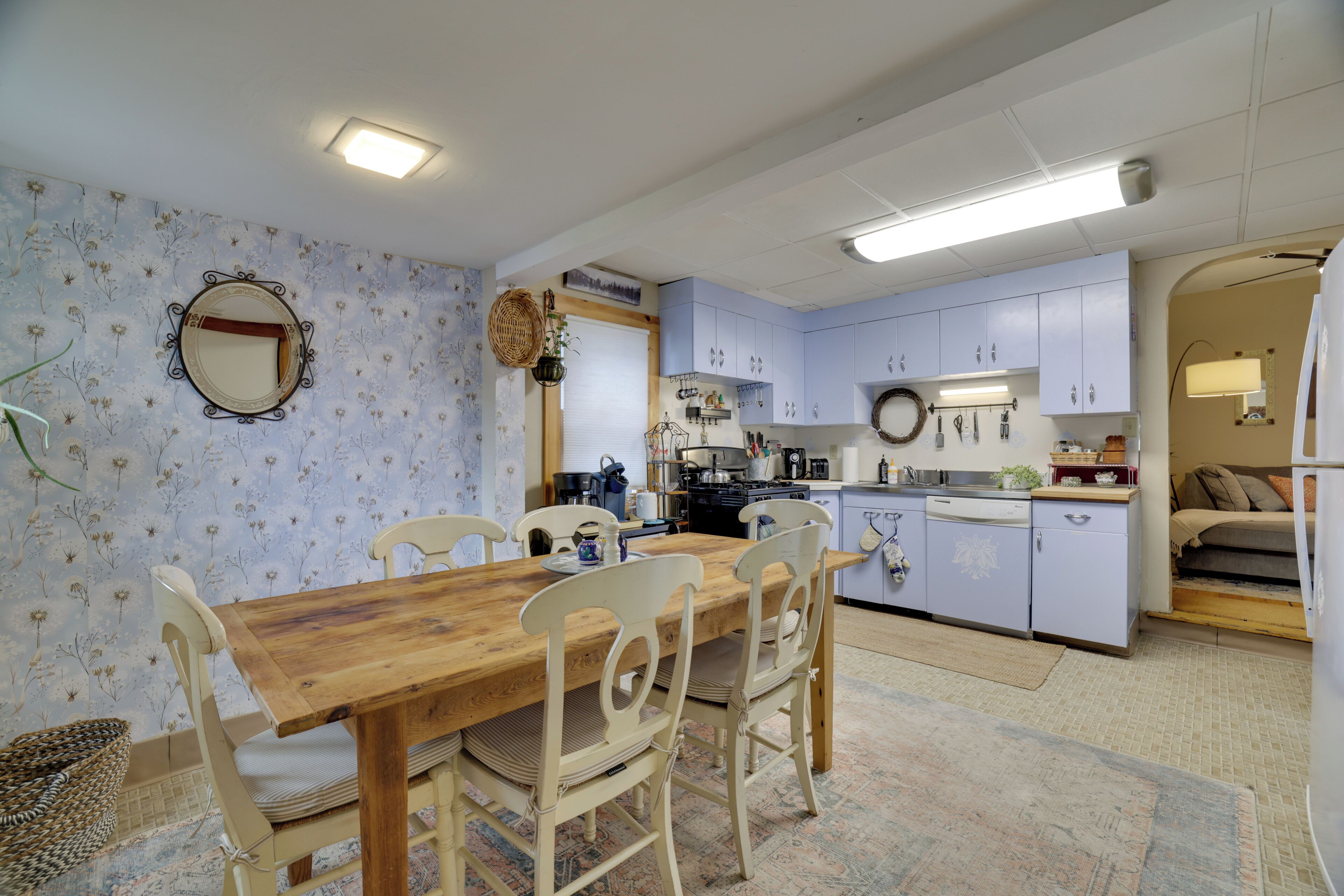 A cozy kitchen with a dining table, chairs, and a variety of kitchen appliances.